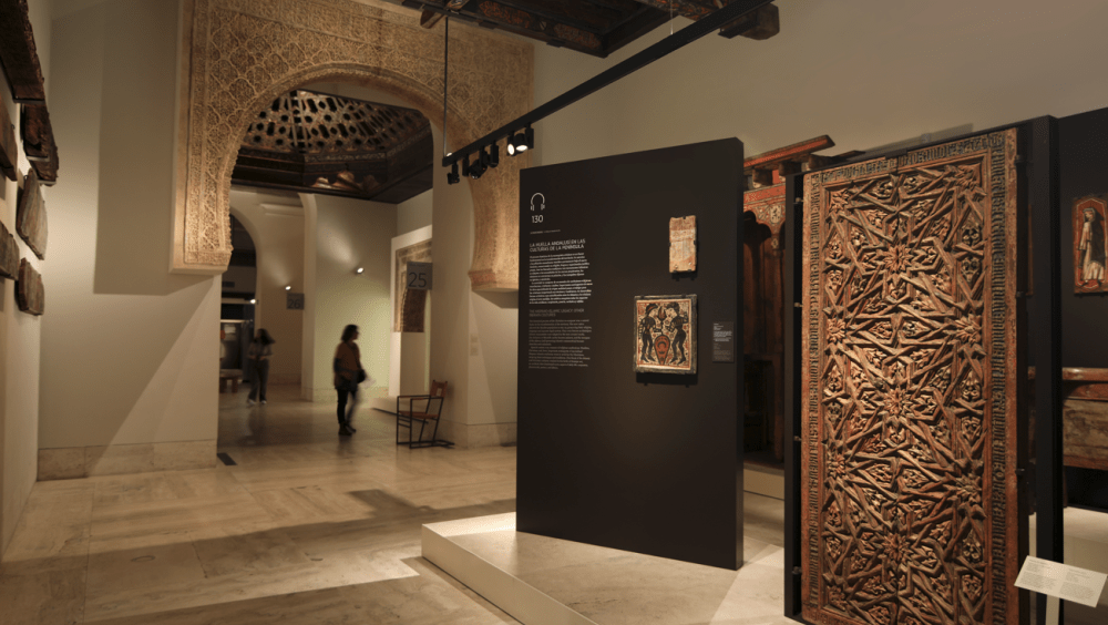 Museum room with a wooden panel on the right and a large white islamic-style archway