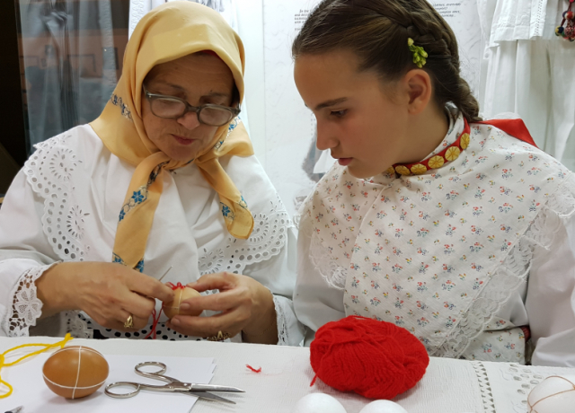 Woman showing to a girl how to die eggs for Easter, Title Keepers of Croatian extended families’ tradition (photo credit, Družina)