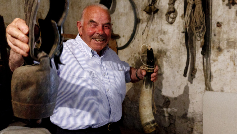 Corne et cloche. Bruno Riccioni montre une cloche pour le taureau châtré (manzirë) et une corne gravée de vache de Maremme utilisée par les bergers comme récipient pour l’huile. Photo de Gianluca Pisciaroli, Fano Adriano (TE), 13 juillet 2011, Archives Centro Studi Don Nicola Jobbi/Bambun