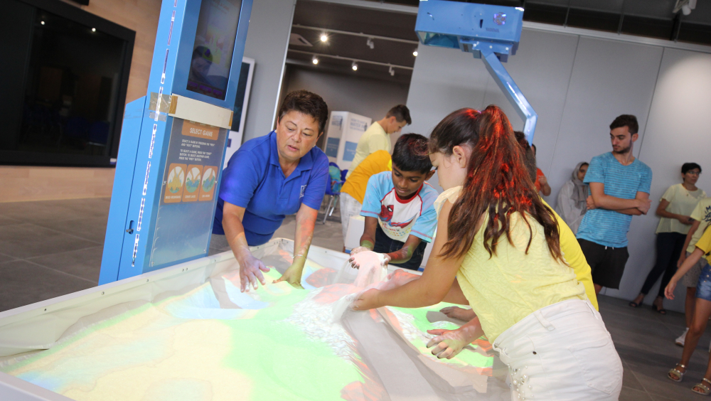 Children playing on one of the interactive sandboxes (creating valleys and waterways).