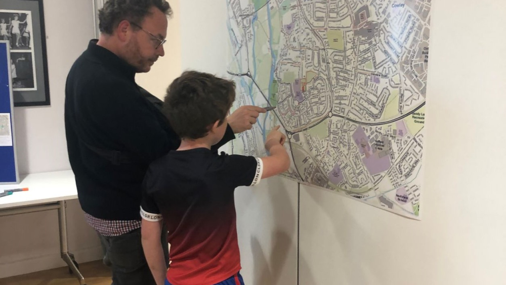 Two people pointing at a large printed-out map of Rose Hill