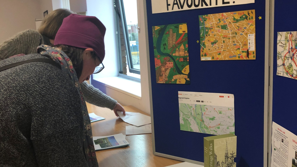 A person writing on a post-in code, standing next to a board which says 'which is your favourite?'