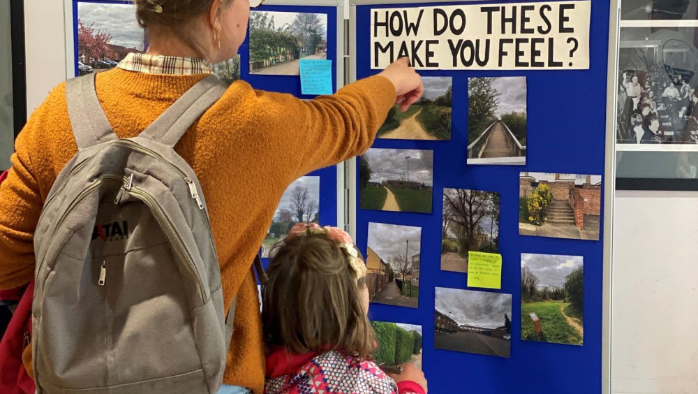 A mother and daughter looking and pointing to a board with images of Rose Hill on them with the text 'how do these make you feel'