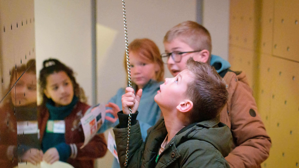 Children exploring the golden Christmas room in the exhibition Feest! In East and West and pulling on a cord that plays music.