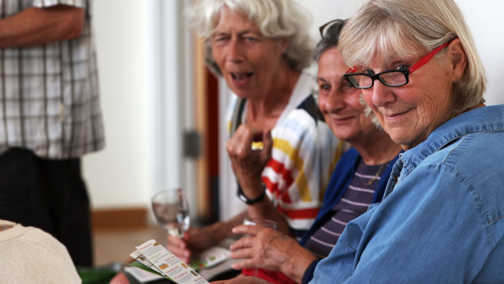 3 ladies chatting and looking at something outside of the image