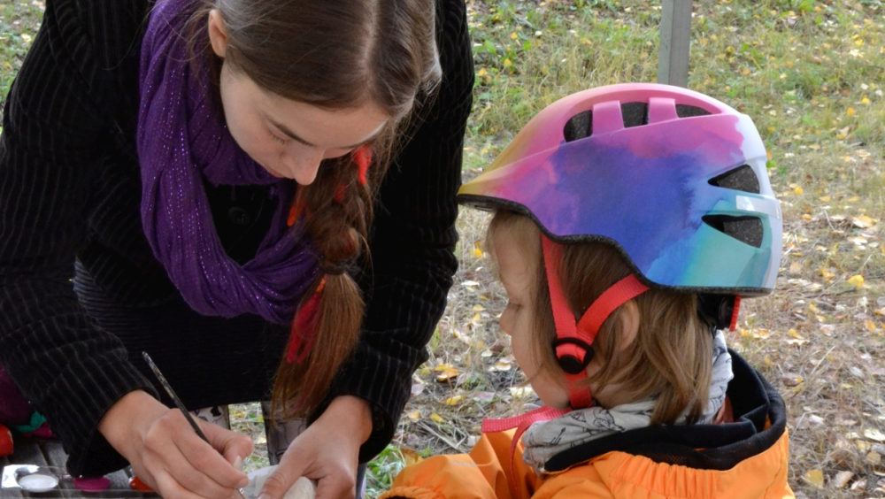 Child getting a Stone Age related painting on her hand during EHD event in 2022. Photo by Riina Koivisto.