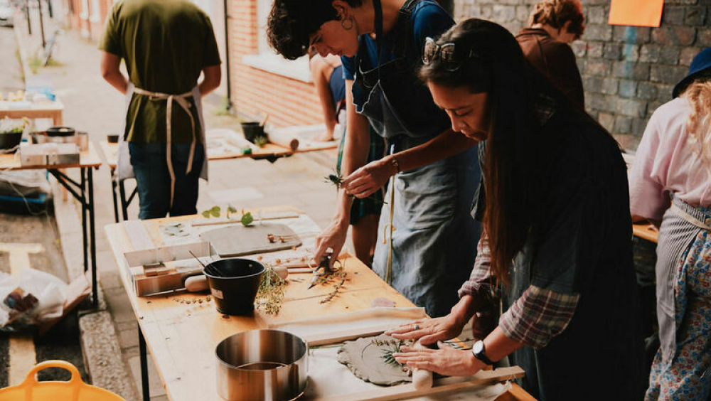 A group of people take part in a craft workshop under the railway arches using clay and dried flowers