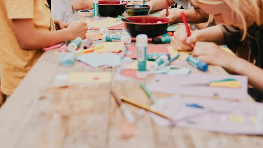 Children taking part in a craft workshop along Beck Road, using bright colouring materials