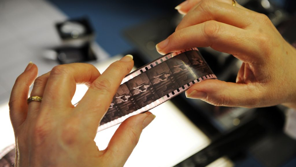Close up of hands holding a strip of film negative.
