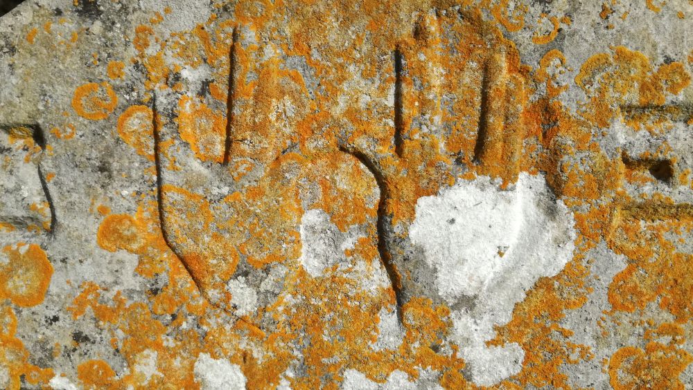 Detail of a headstone showing stylised hands