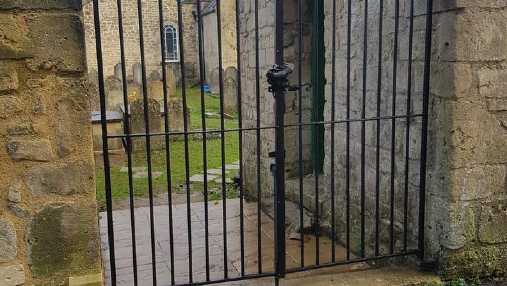 Wrought-iron gates with the burial ground visible beyond