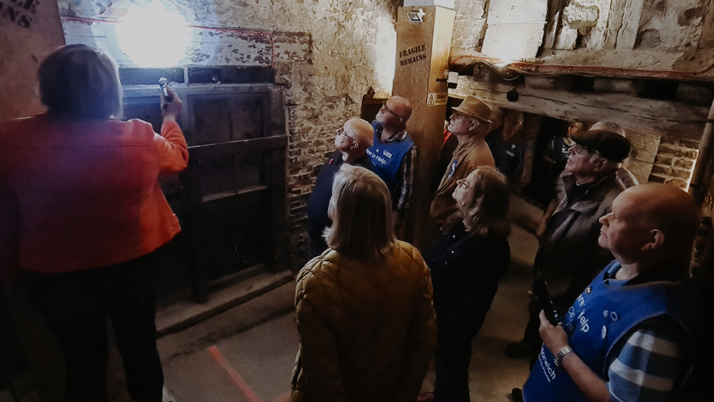 Tour guests marvelling at a weaver's cottage from the 1400s, now hidden underground