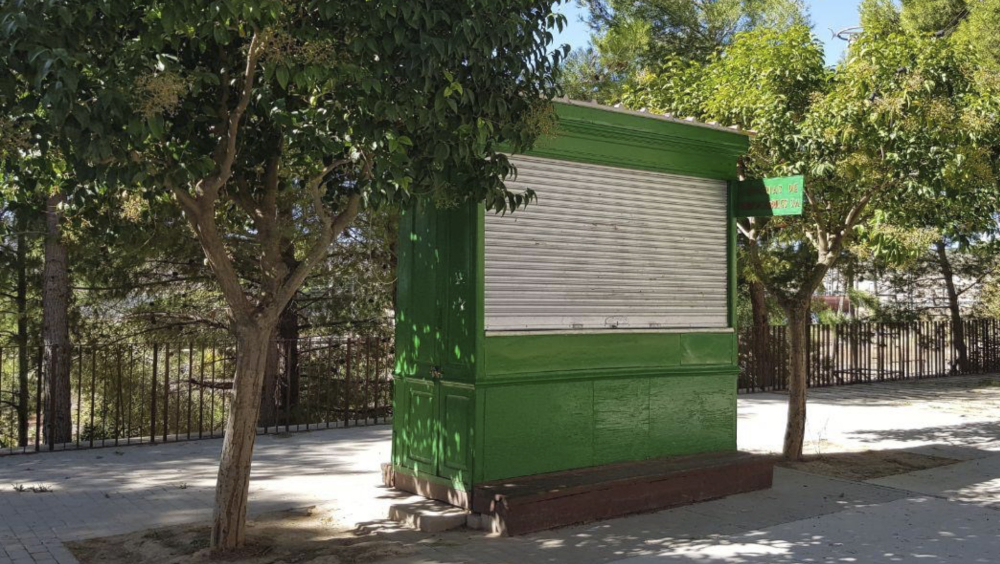 kiosko de prensa verde colocado en la calle con la persiana cerrada