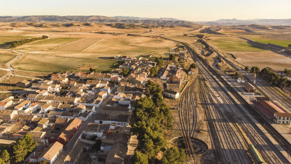 Vista de dron sobre población con vias de tren al atardecer