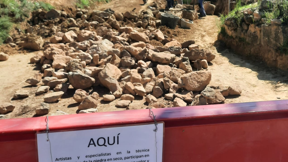 Imagen del desarrollo de las obras  de recuperación de los muros a piedra seca por las pareteras y artistas Margot, Inma y Sandrine junto en el camino de Castilsabás a Barluenga