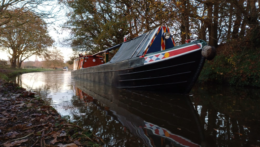 A traditional English canal narrowboat approaches the camera