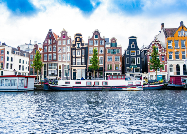 Historic waterfront buildings in Amsterdam (credit, Tobias Kordt via Unsplash)