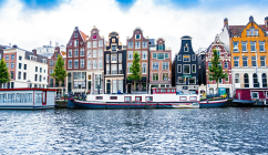 Historic waterfront buildings in Amsterdam (credit, Tobias Kordt via Unsplash)