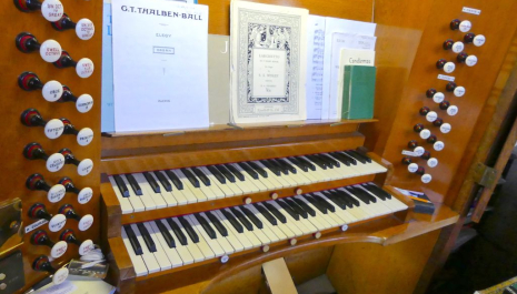 Close up view of an organ console, with keyboard and buttons, with music laid out ready to play.