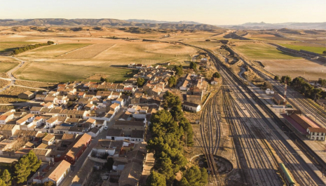 Vista de dron sobre población con vias de tren al atardecer
