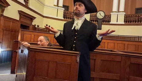 A man in costume in a mock trail in a court room.