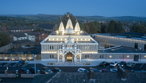 The main entrance of Shree Swaminarayan Mandir Oldham lit up at night.